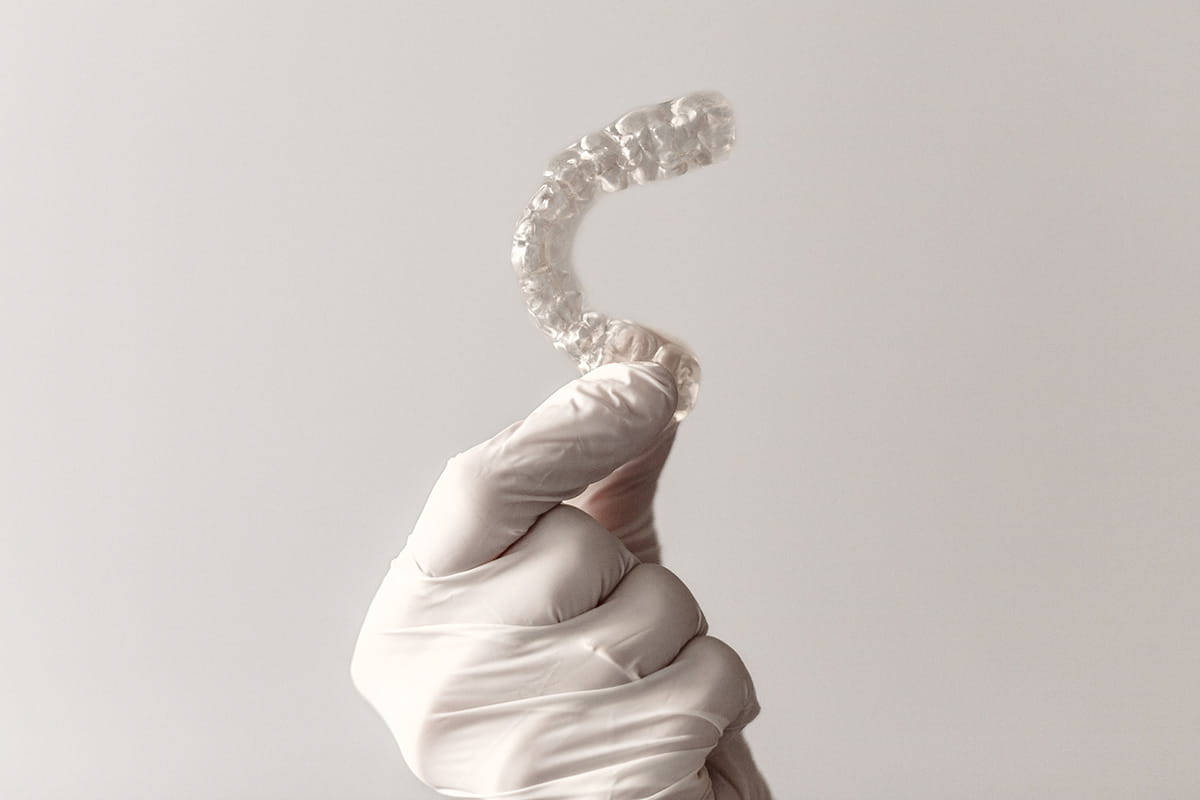 Gloved hand holding a clear Invisalign aligner tray at Vinings Modern Dentistry