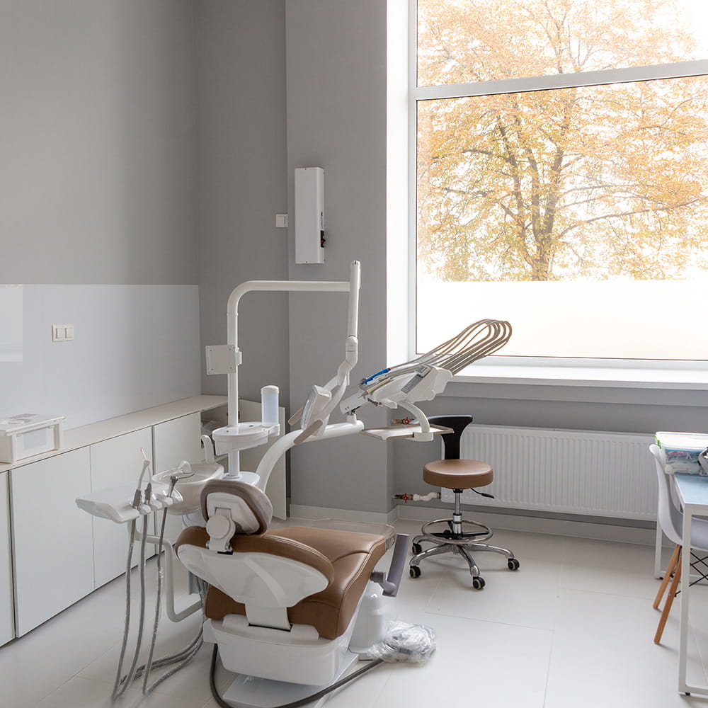 Empty dental treatment room at Vinings Modern Dentistry with a reclined chair, overhead light, and instruments beside a window