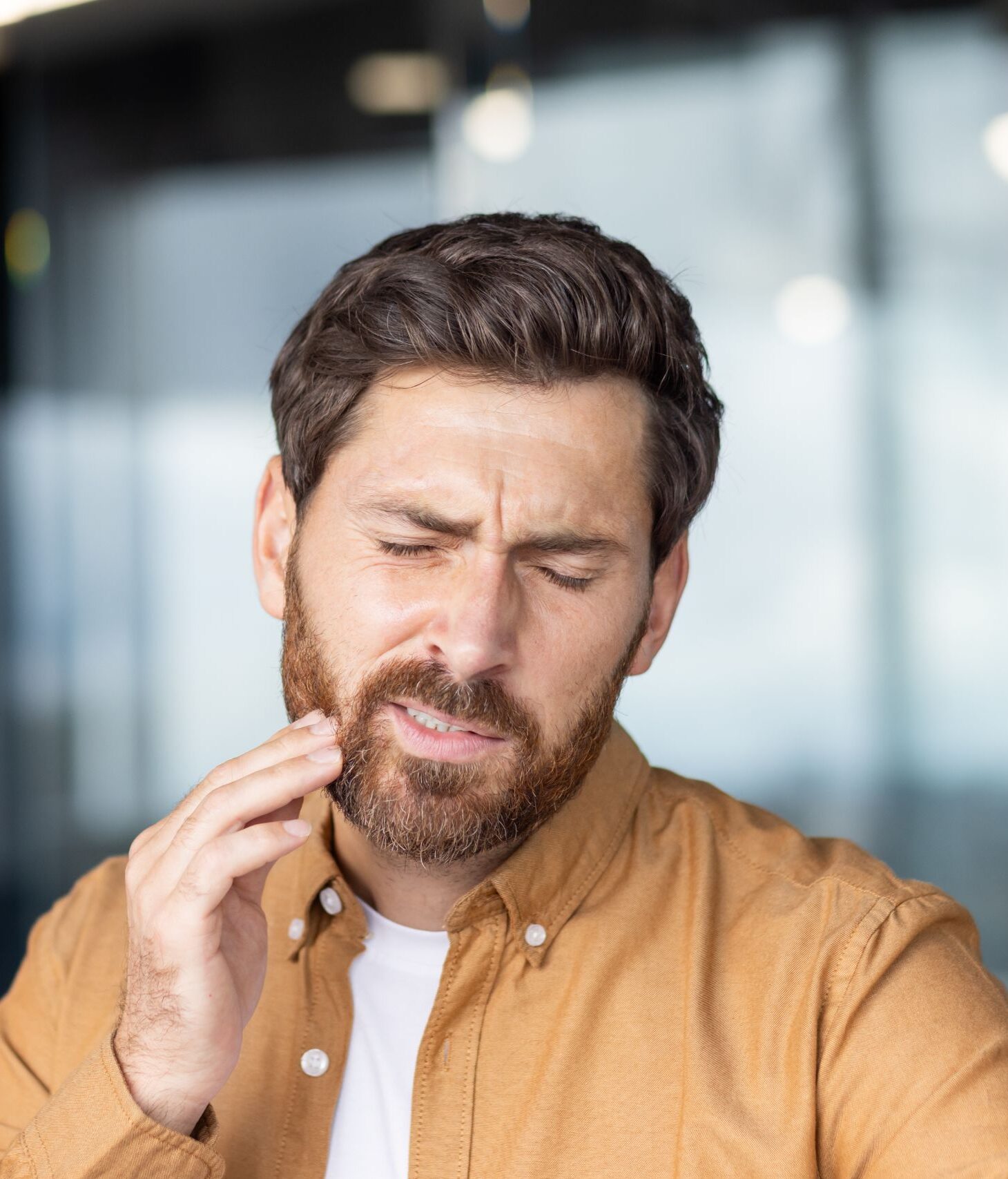 Man wincing and holding his jaw in pain from a toothache