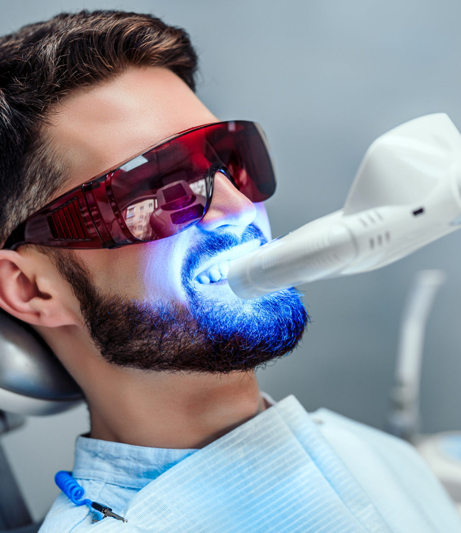 Close up view of man undergoing laser tooth whitening treatment to remove stains and discoloration.