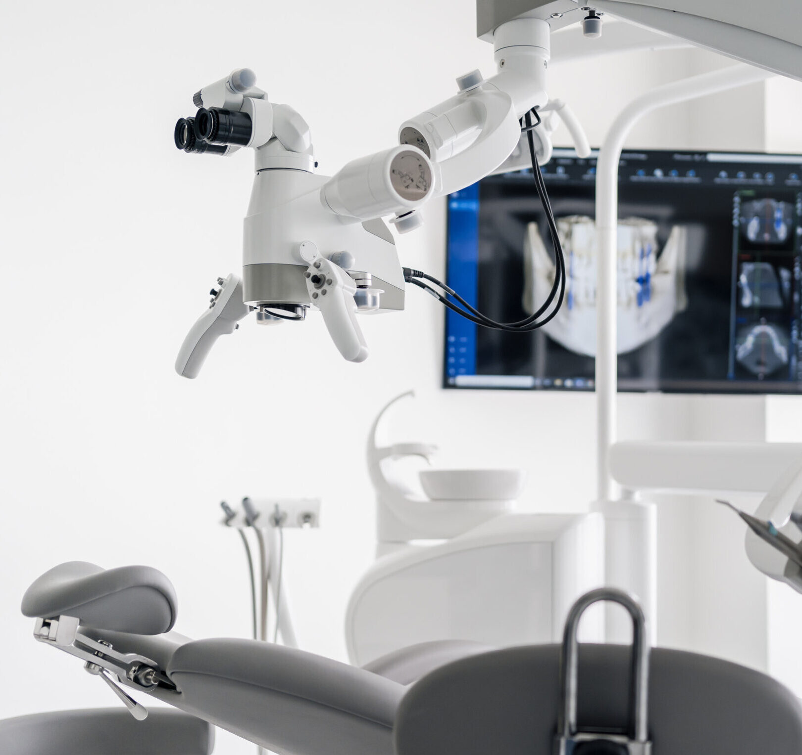 Interior of dental practice room with chair, lamp, dental scan on the display and stomatological tools