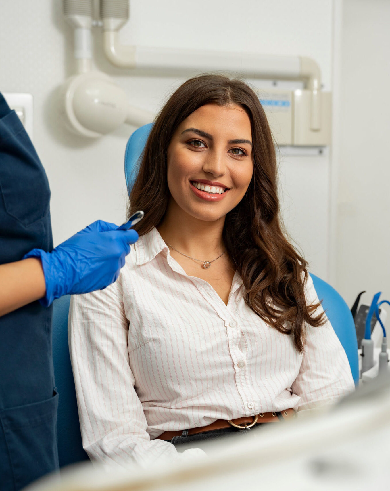 Satisfied patient sitting in dentist chair. Gorgeous young woman in dental clinic smiling from a chair next to dentist