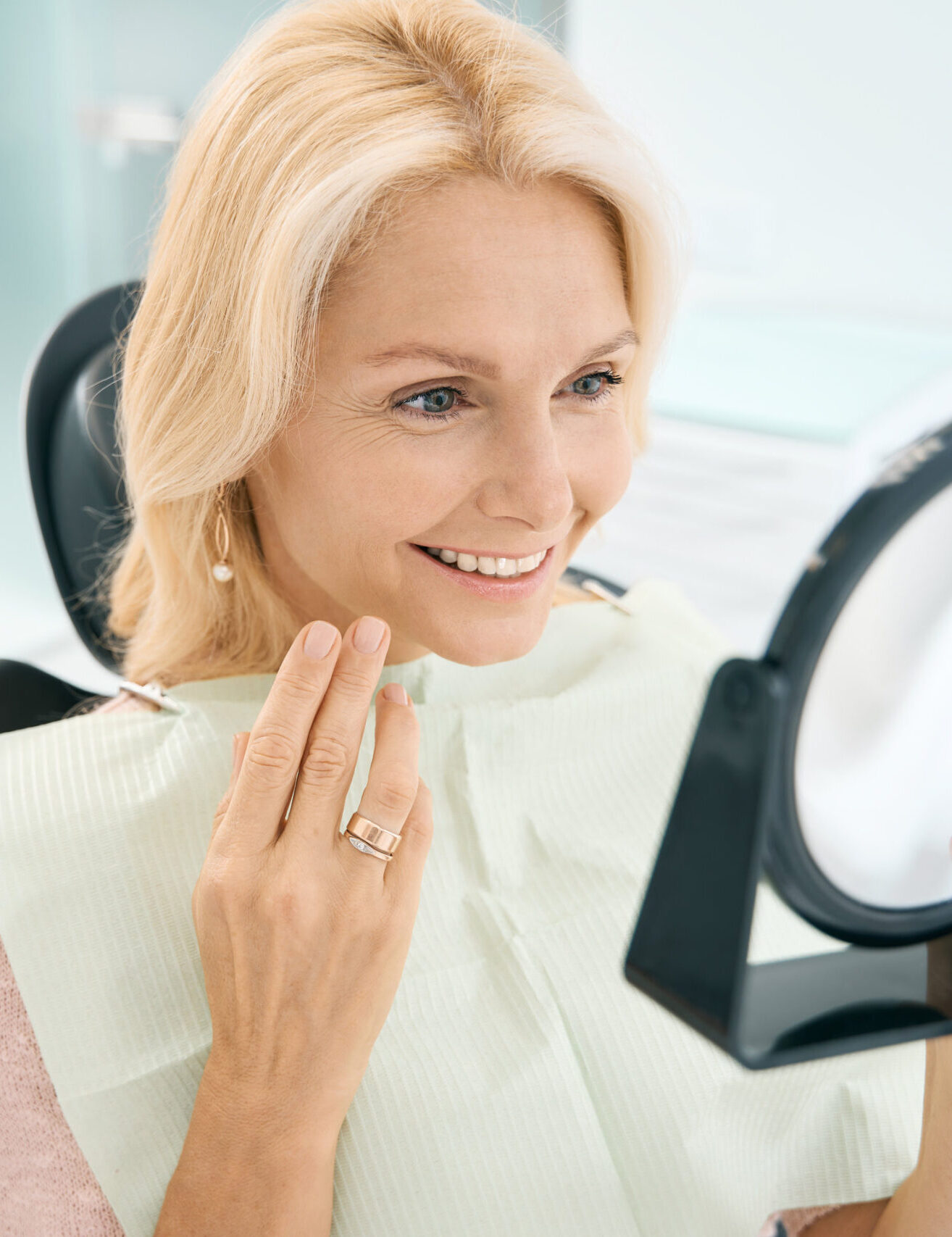 Close up portrait of pretty Caucasian female enjoying her beautiful smile after the dentistry treatment in medicine center