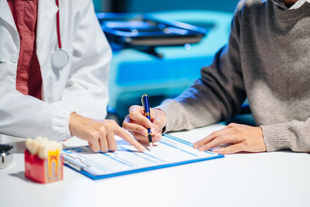 Dentist and patient reviewing a treatment form next to a tooth cross-section model