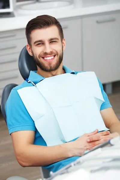 Smiling patient with a bib seated in a dental chair during a cosmetic dentistry visit at Vinings Modern Dentistry