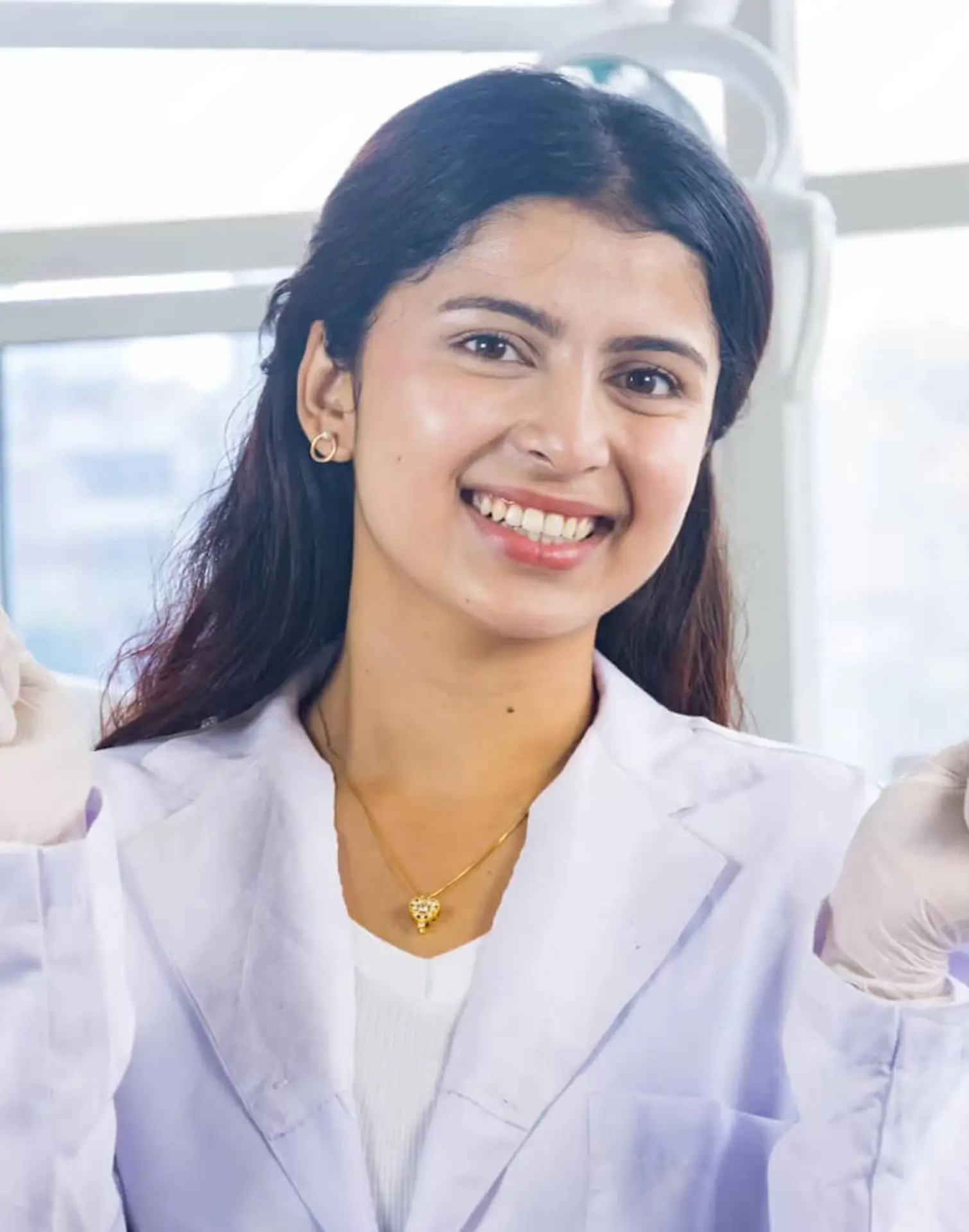 Smiling dentist in a white coat and gloves in a treatment room at Vinings Modern Dentistry