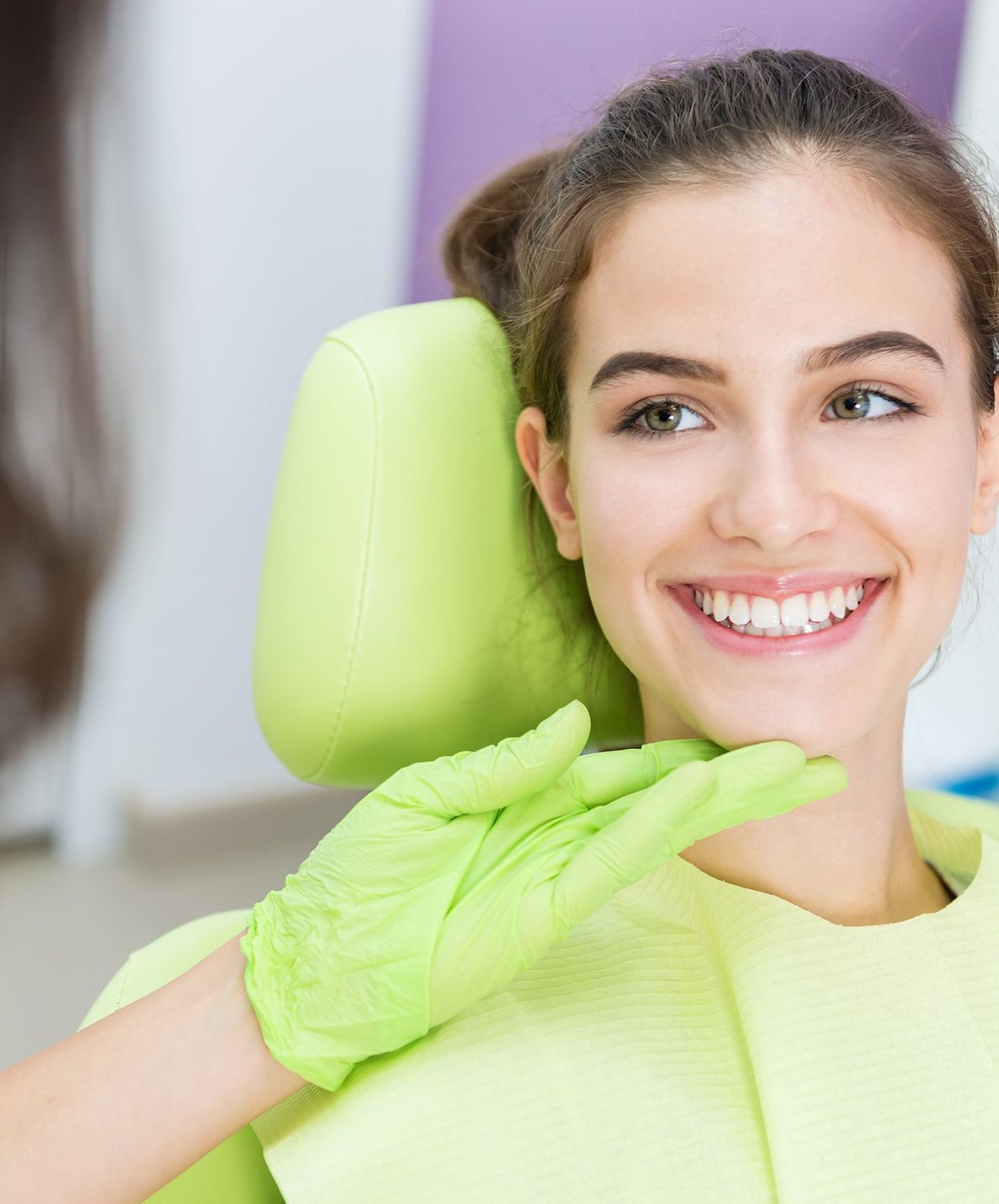 Smiling woman in a dental chair considering porcelain veneers