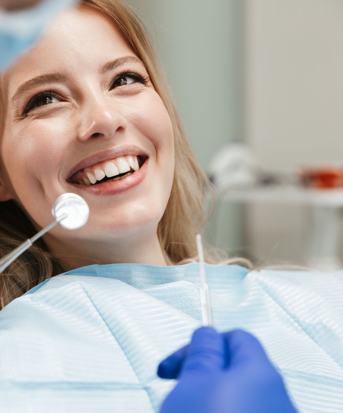Smiling woman at a dental exam while considering porcelain veneers