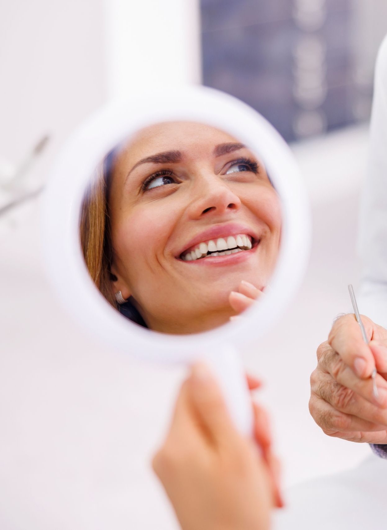 Patient viewing her smile in a mirror with a dentist during a consultation