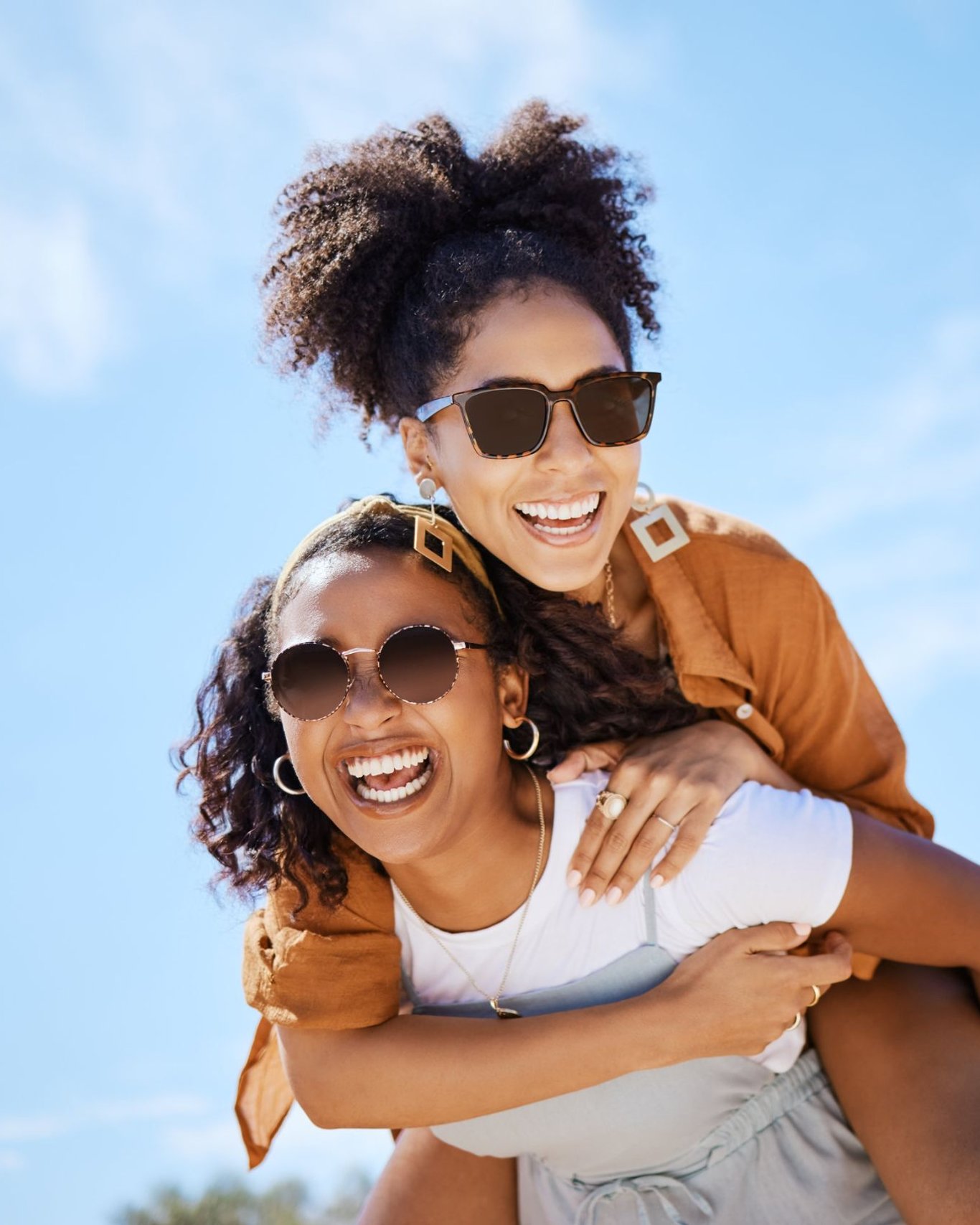 Two smiling friends outdoors with bright, confident smiles