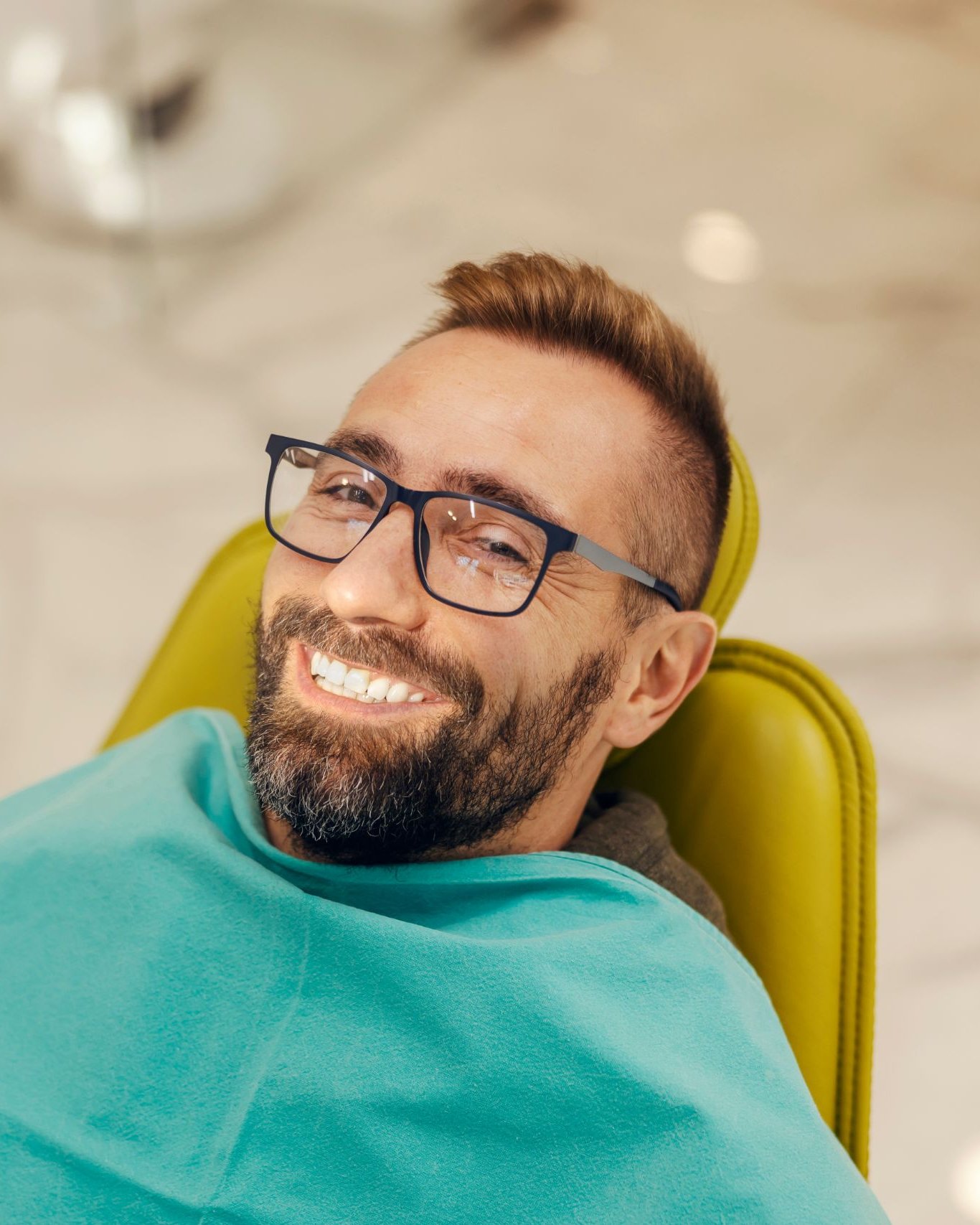Smiling man in glasses seated in a dental chair before whitening