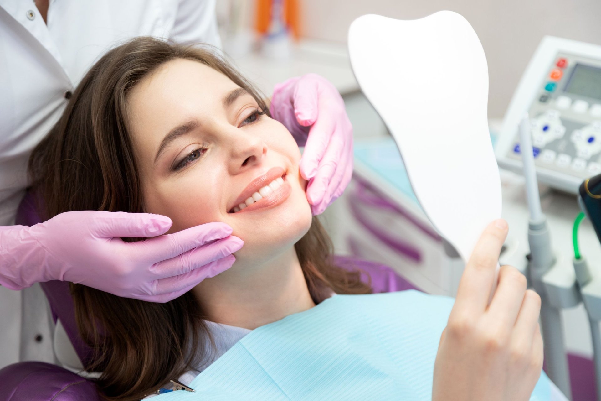 Patient looking in a hand mirror during a cosmetic dentistry visit