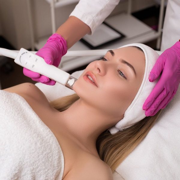 Be always young! Side-view portrait of a young woman with a towel on her head lying on a table getting a skin treatment in healthy beauty spa salon.