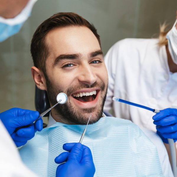 Image of a handsome happy young man sitting in medical dentist center. Looking at camera.